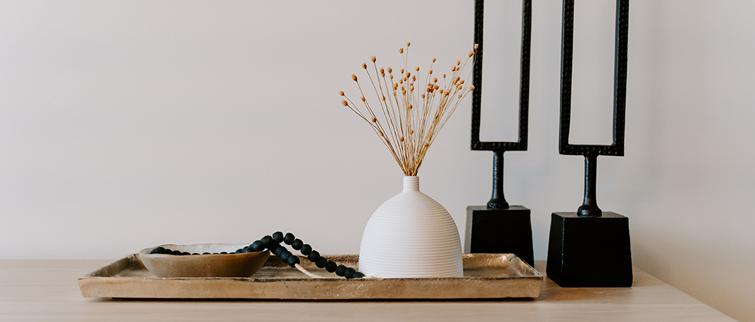 Table with metal tray, sculptures, and pot with plants.