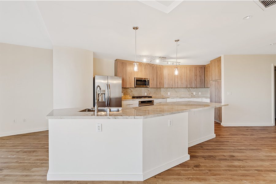 Open-concept kitchen with an island, wood & white cabinets, marble countertops, and stainless steel appliances.